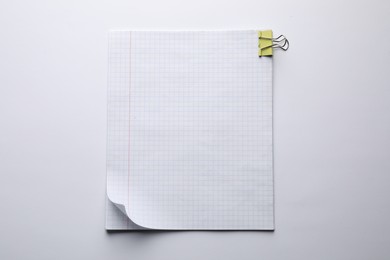 Checkered paper sheets with binder clip on white background, top view