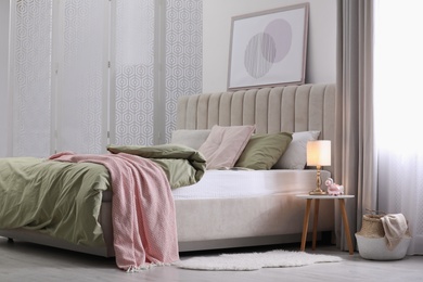 Comfortable bed with new pistachio linens in modern room interior