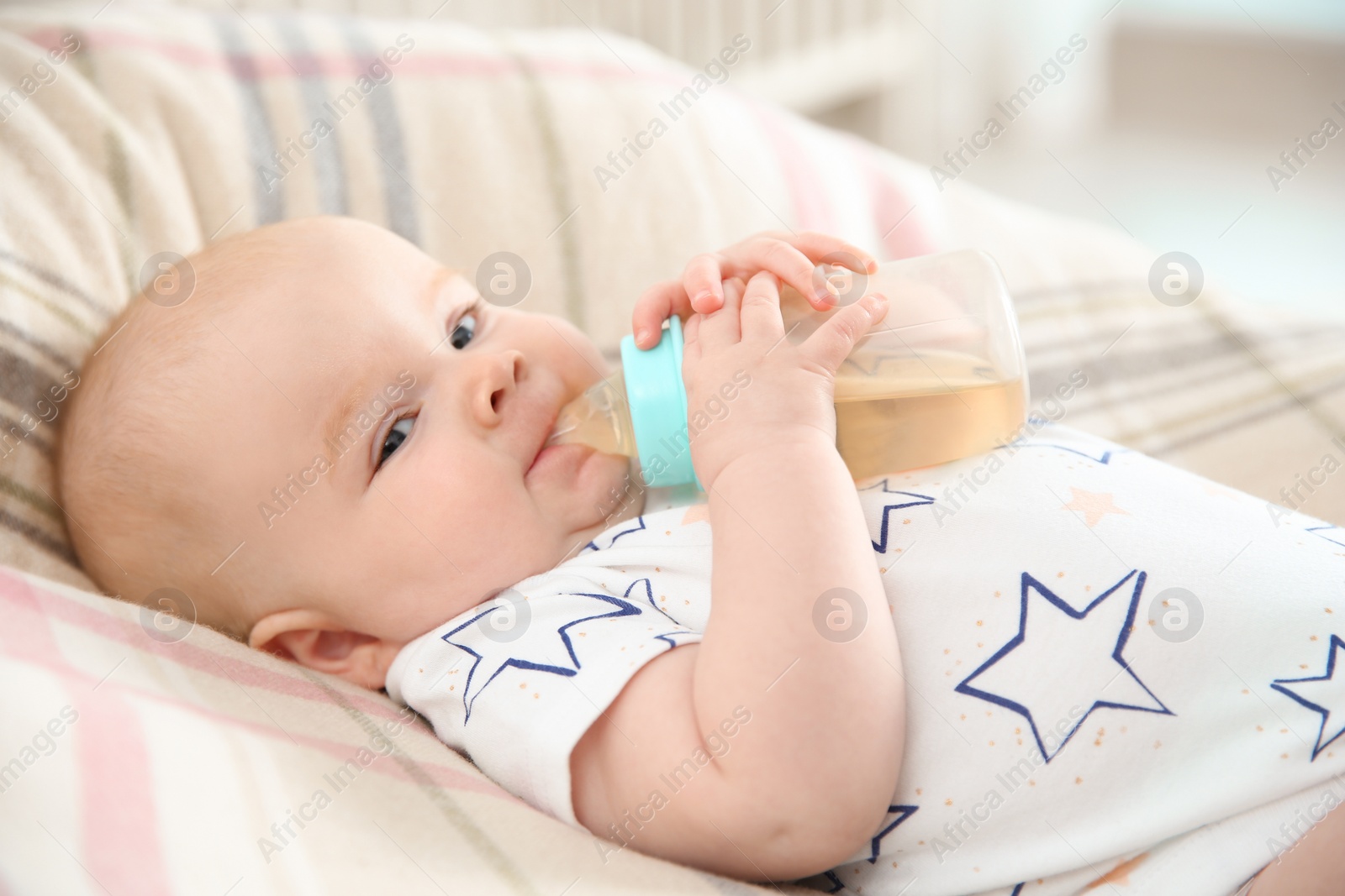 Photo of Pretty baby drinking from bottle on bed at home