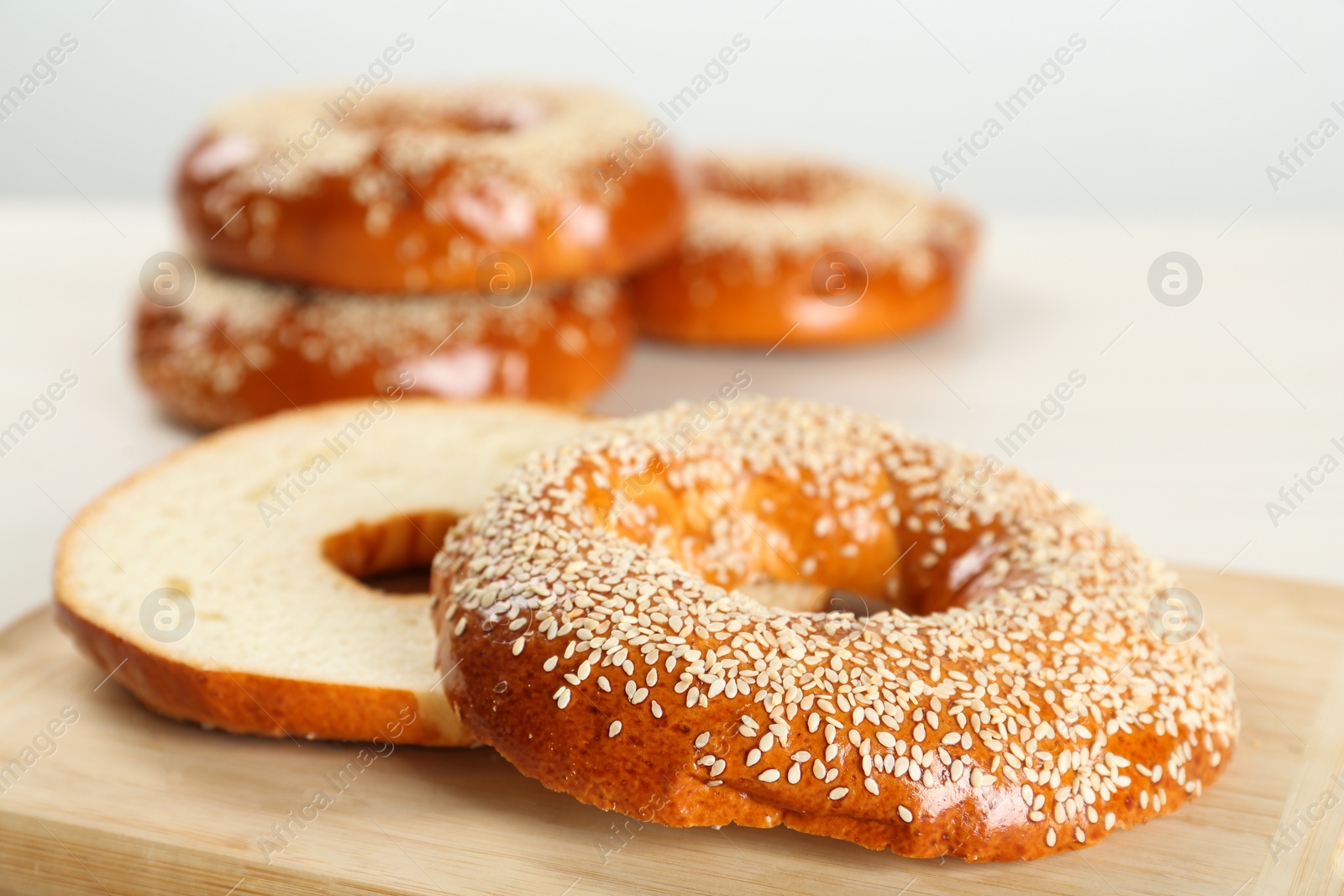 Photo of Delicious fresh halved bagel on wooden board, closeup