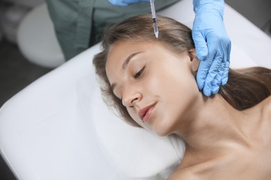 Beautiful woman getting facial injection in salon