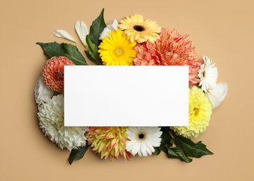 Flat lay composition with beautiful dahlia flowers and blank card on beige background, flat lay. Space for text