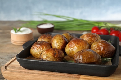 Photo of Delicious hot baked potato with sour cream on wooden table