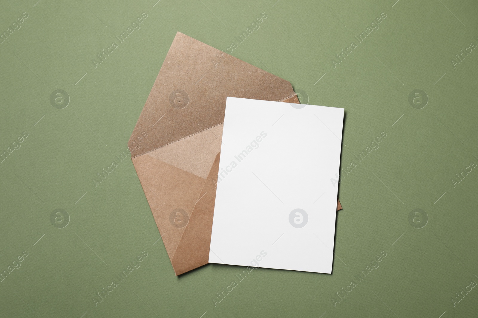 Photo of Letter envelope and card on green background, top view. Space for text
