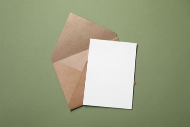 Letter envelope and card on green background, top view. Space for text