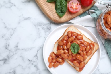 Toast with delicious canned beans on white marble table, flat lay. Space for text