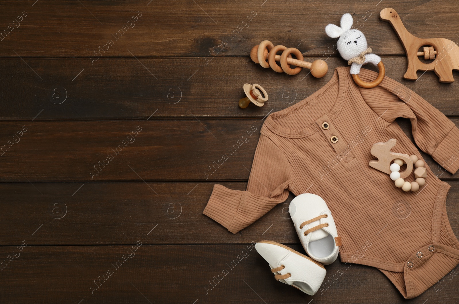Photo of Flat lay composition with baby clothes and accessories on wooden table. Space for text