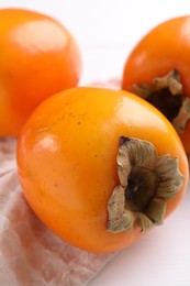 Photo of Delicious ripe persimmons on white table, closeup