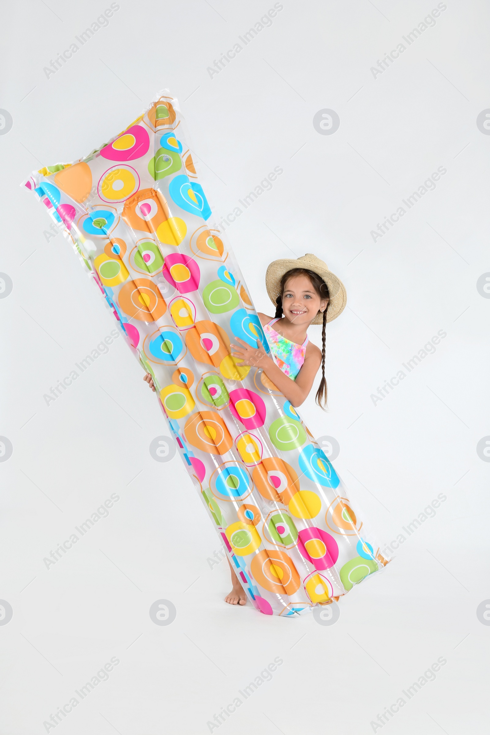 Photo of Cute little child in beachwear with bright inflatable mattress on white background