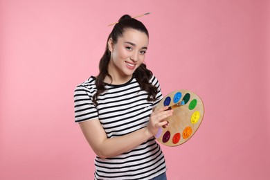 Photo of Woman with painting tools on pink background. Young artist