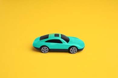 Photo of One turquoise car on yellow background. Children`s toy