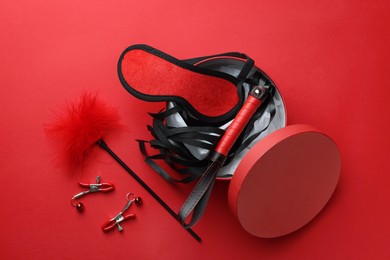 Photo of Gift box with different sex toys on red background, flat lay