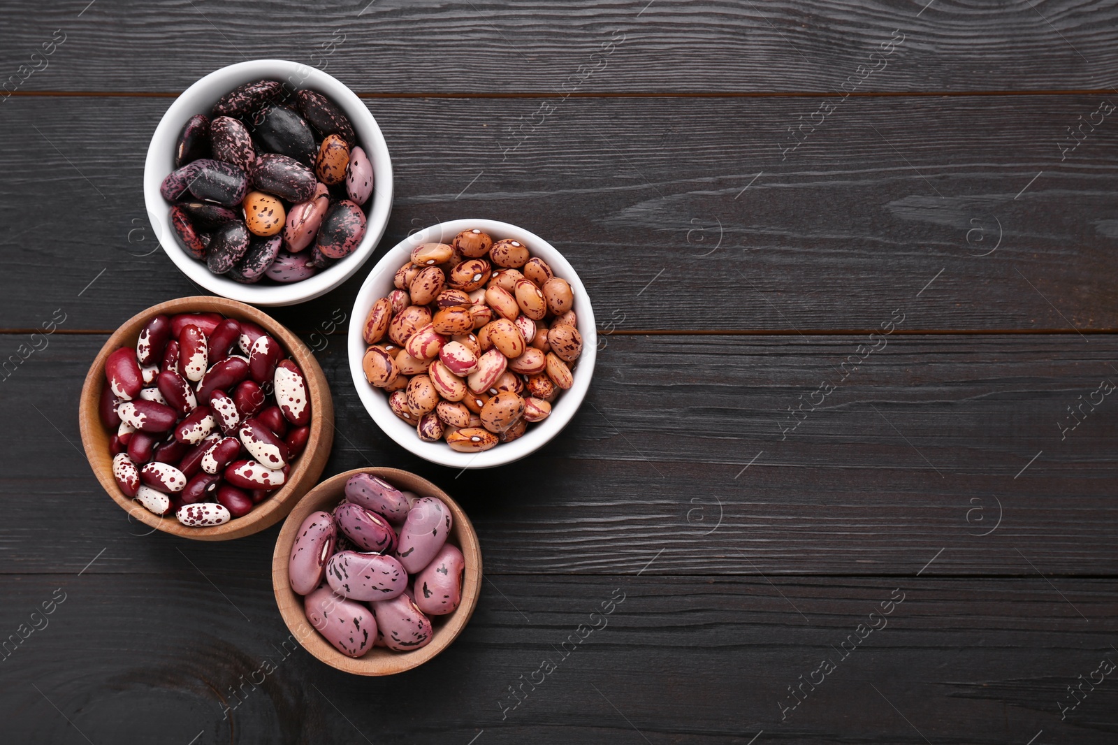 Photo of Different kinds of dry kidney beans on wooden table, flat lay. Space for text