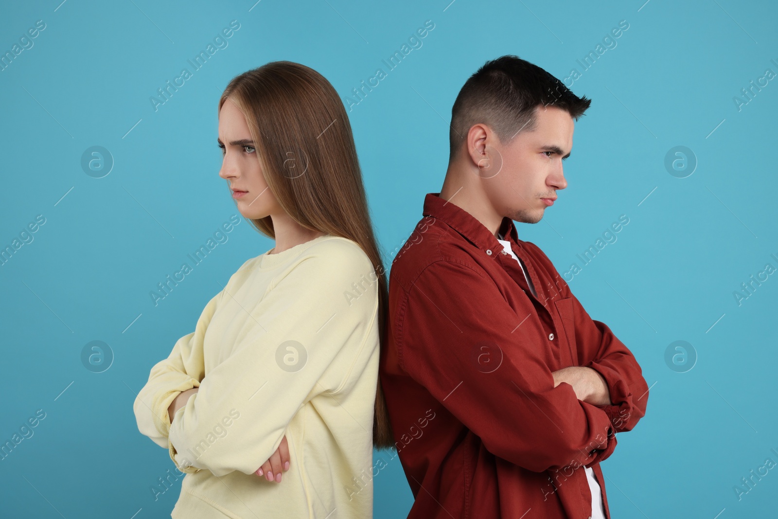Photo of Portrait of resentful couple with crossed arms on light blue background