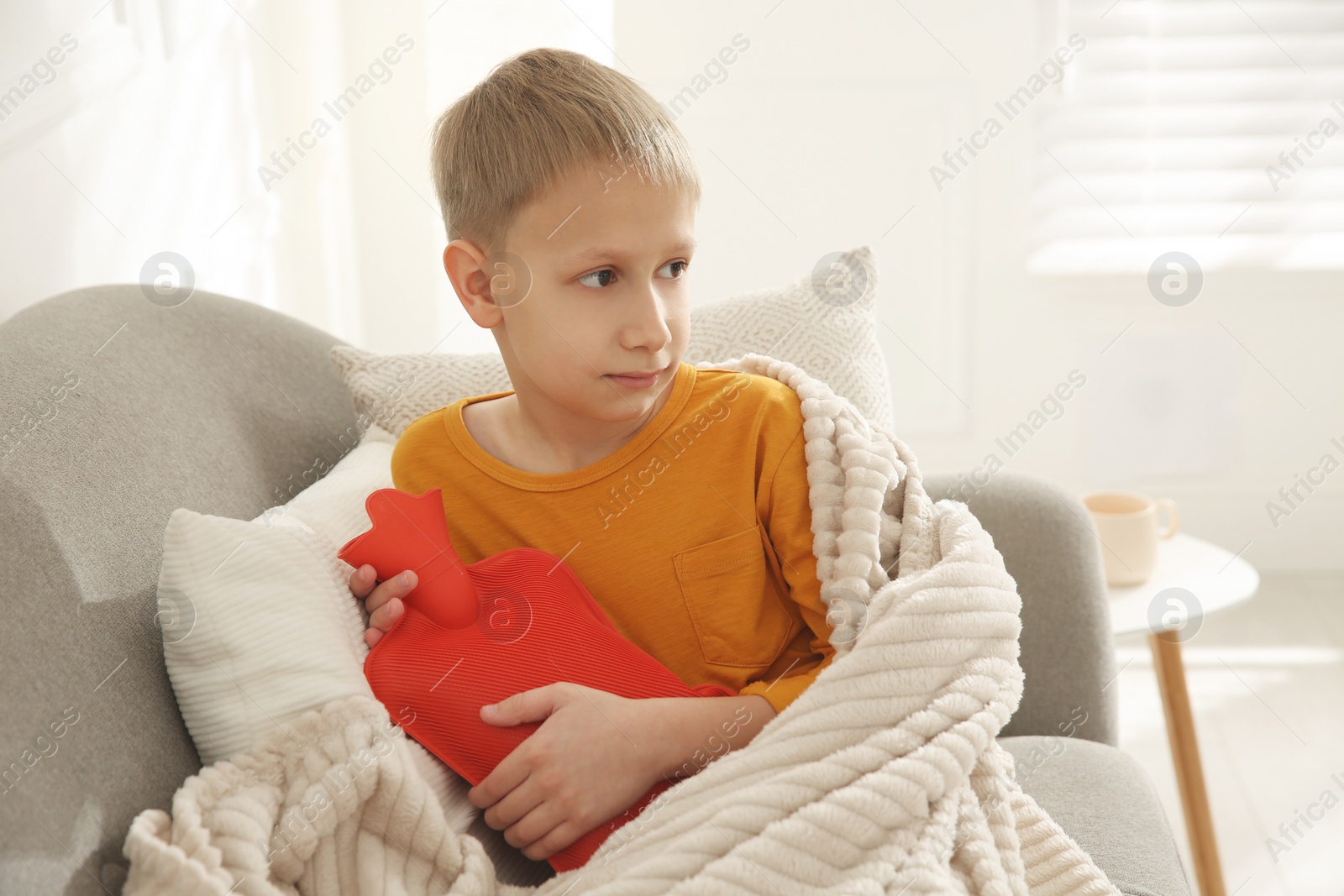 Photo of Ill boy with hot water bottle suffering from cold at home