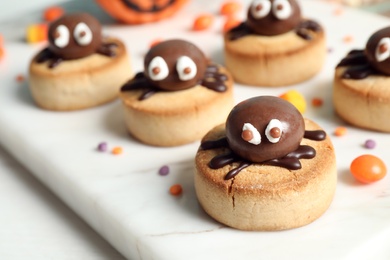 Delicious biscuits with chocolate spiders on white table, closeup. Halloween celebration