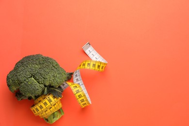 Photo of Broccoli and measuring tape on coral background, top view with space for text. Weight loss