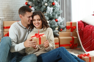 Man presenting Christmas gift to his girlfriend at home 