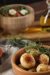 Delicious grilled potatoes with tarragon and salad on table, selective focus