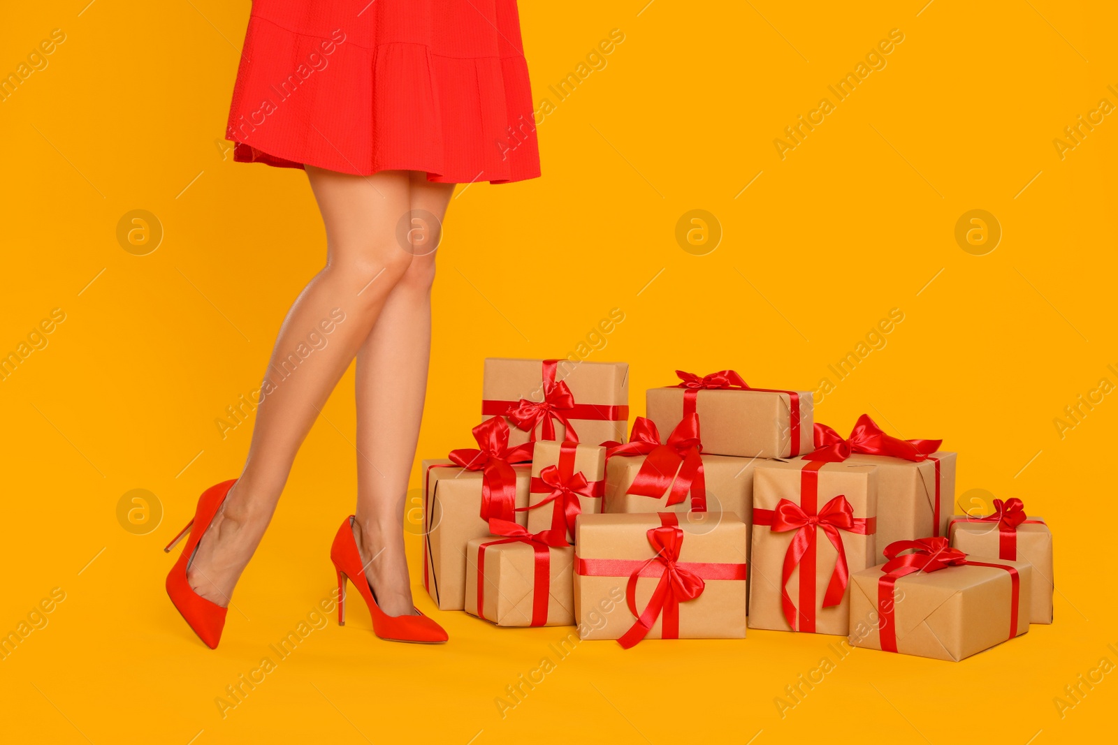 Photo of Woman and gift boxes on yellow background, closeup. Black Friday
