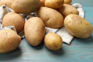 Photo of Raw fresh potatoes and napkin on light blue wooden table