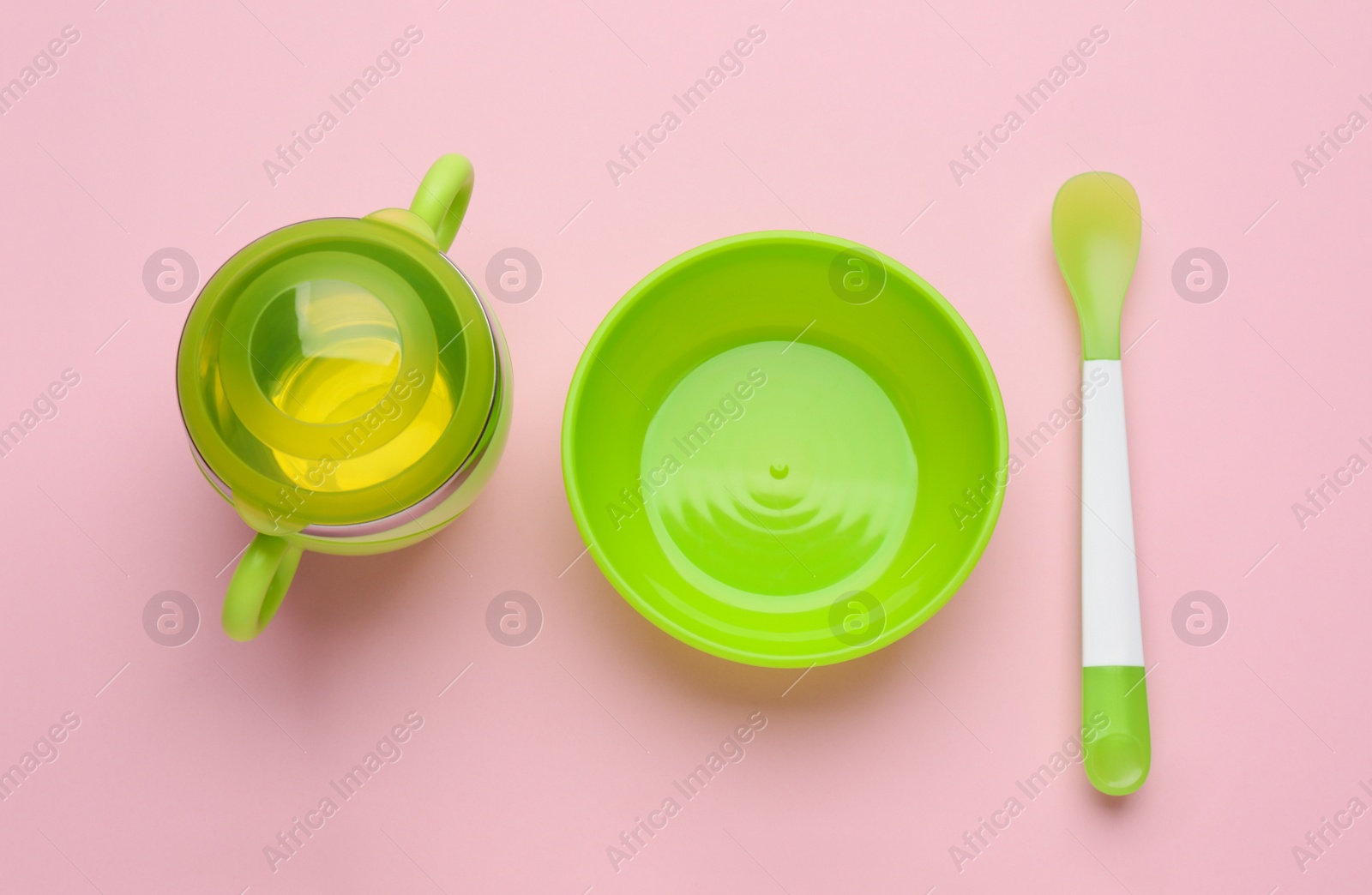 Photo of Set of plastic dishware on pink background, flat lay. Serving baby food