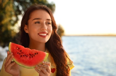 Photo of Beautiful young woman with watermelon near river. Space for text