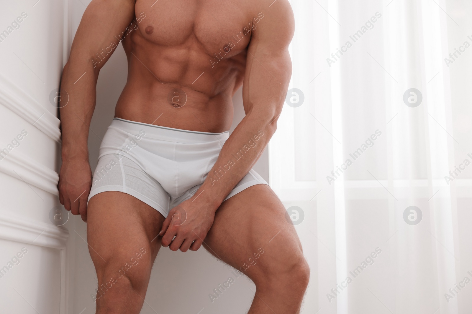 Photo of Young man in stylish underwear near white wall indoors, closeup. Space for text