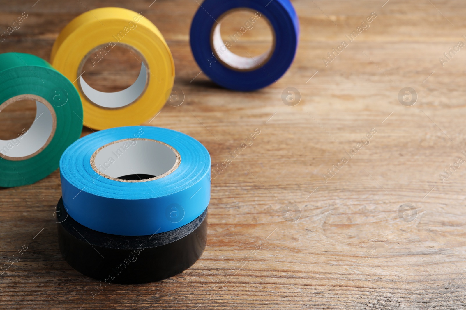 Photo of Colorful insulating tapes on wooden table, space for text