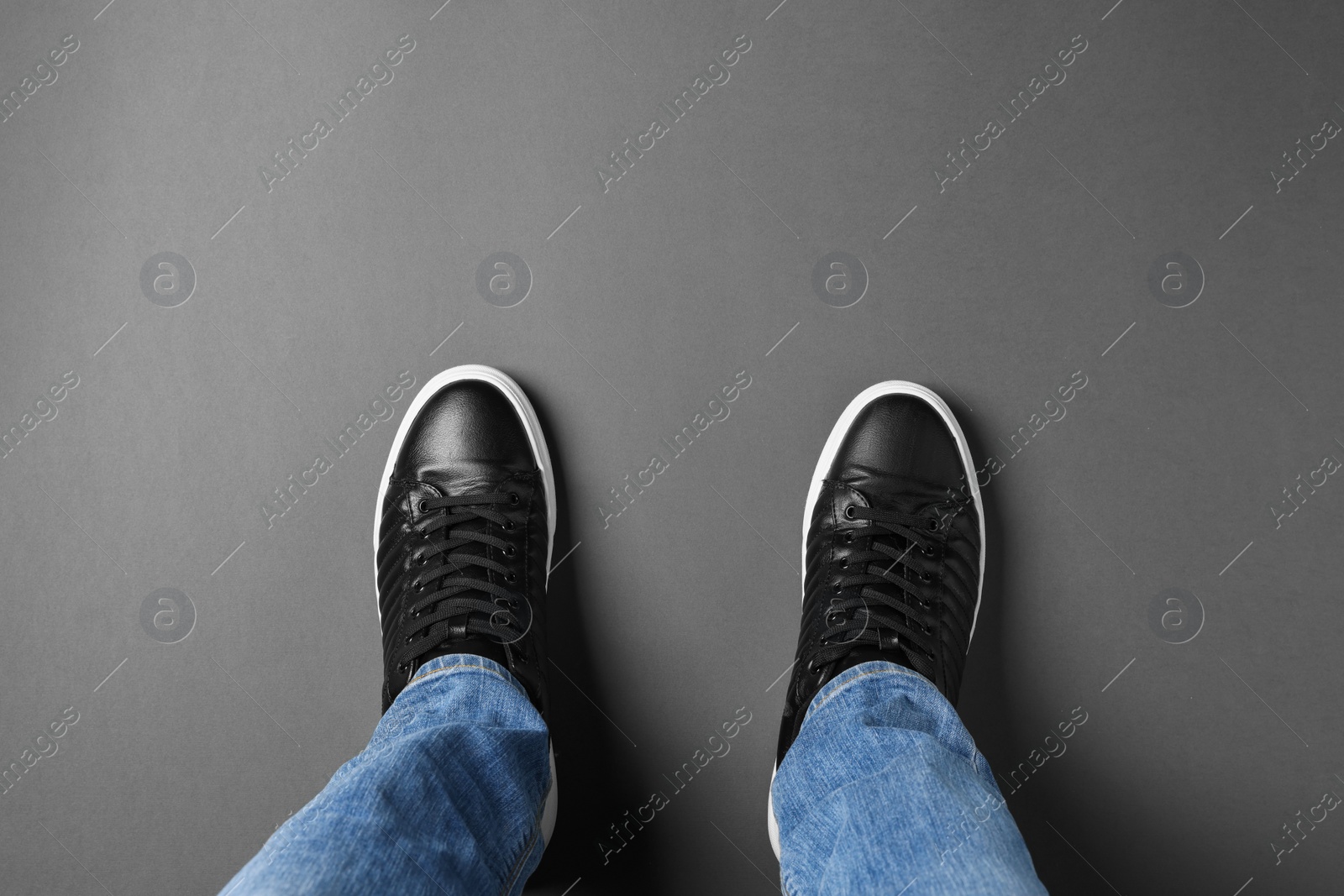 Photo of Man in black leather shoes standing on grey background, top view