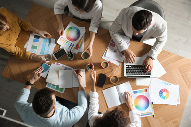 Team of professional designers working together at table, top view