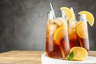 Photo of Glasses of refreshing iced tea on wooden table against grey background. Space for text