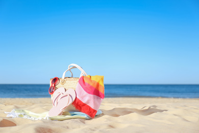 Photo of Stylish beach accessories for summer vacation on sand near sea. Space for text
