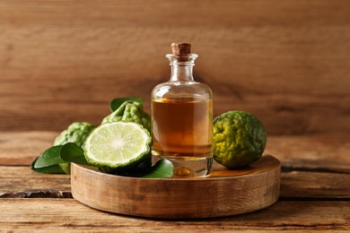 Photo of Glass bottle of bergamot essential oil on wooden table