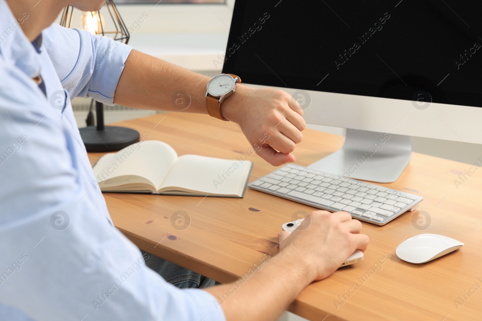 Photo of Man checking time at desk in office, closeup. Being late