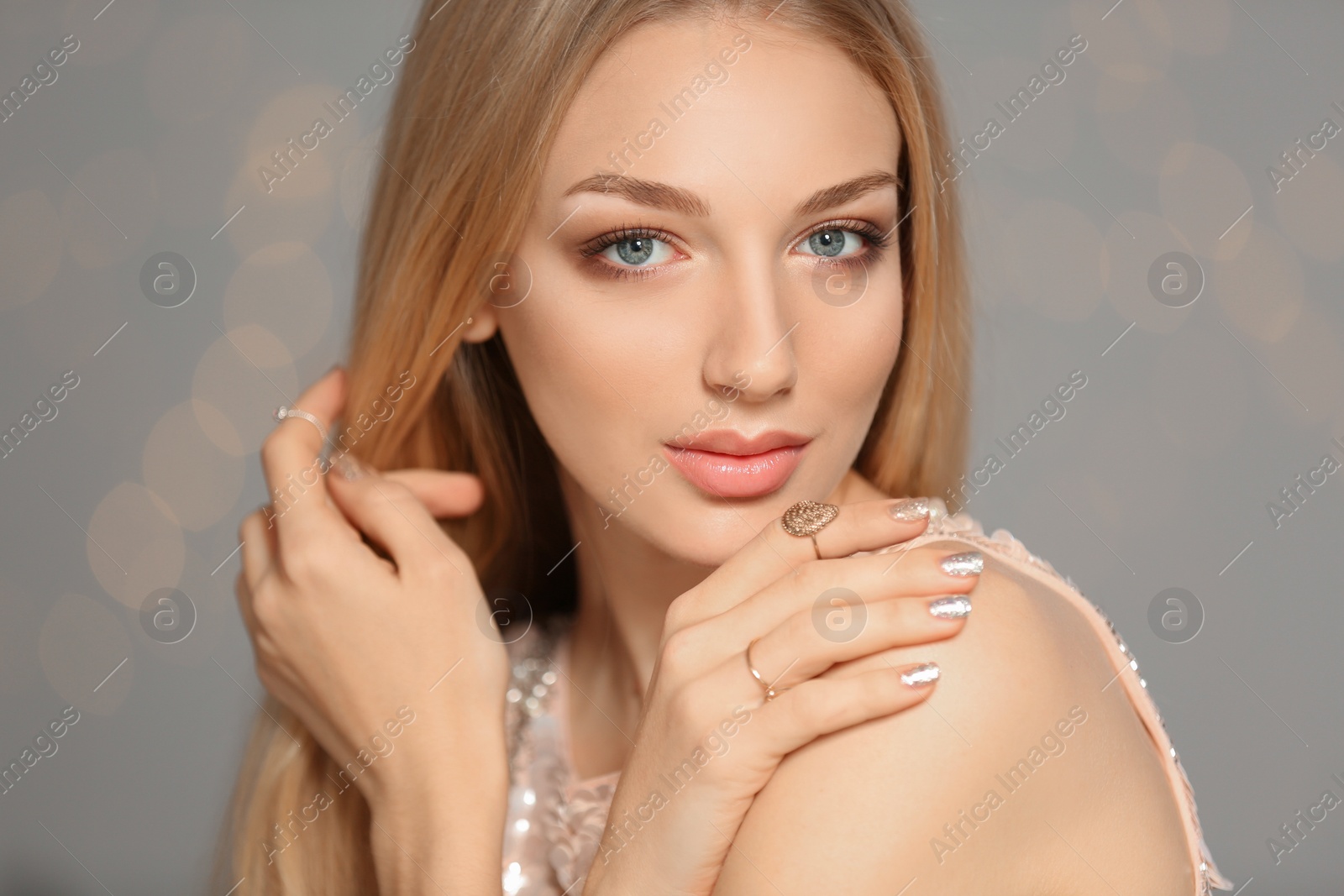 Photo of Beautiful young woman with shiny manicure on blurred background. Nail polish trends