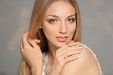 Beautiful young woman with shiny manicure on blurred background. Nail polish trends