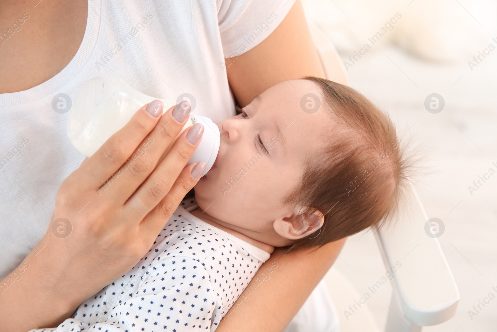 Photo of Woman feeding her baby from bottle at home, closeup