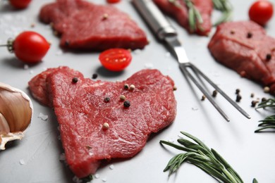 Photo of Fresh raw meat steaks and spices on light grey table, closeup