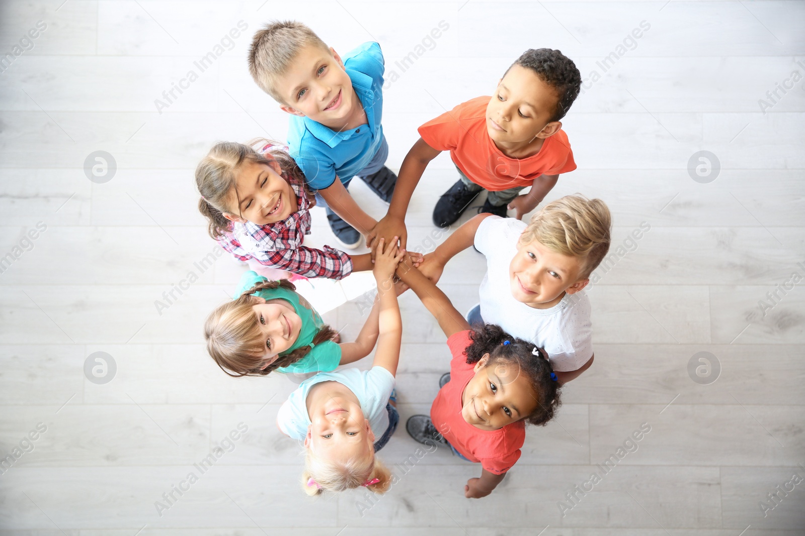 Photo of Little children putting their hands together indoors, top view. Unity concept