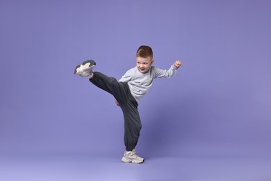 Happy little boy dancing on violet background. Space for text