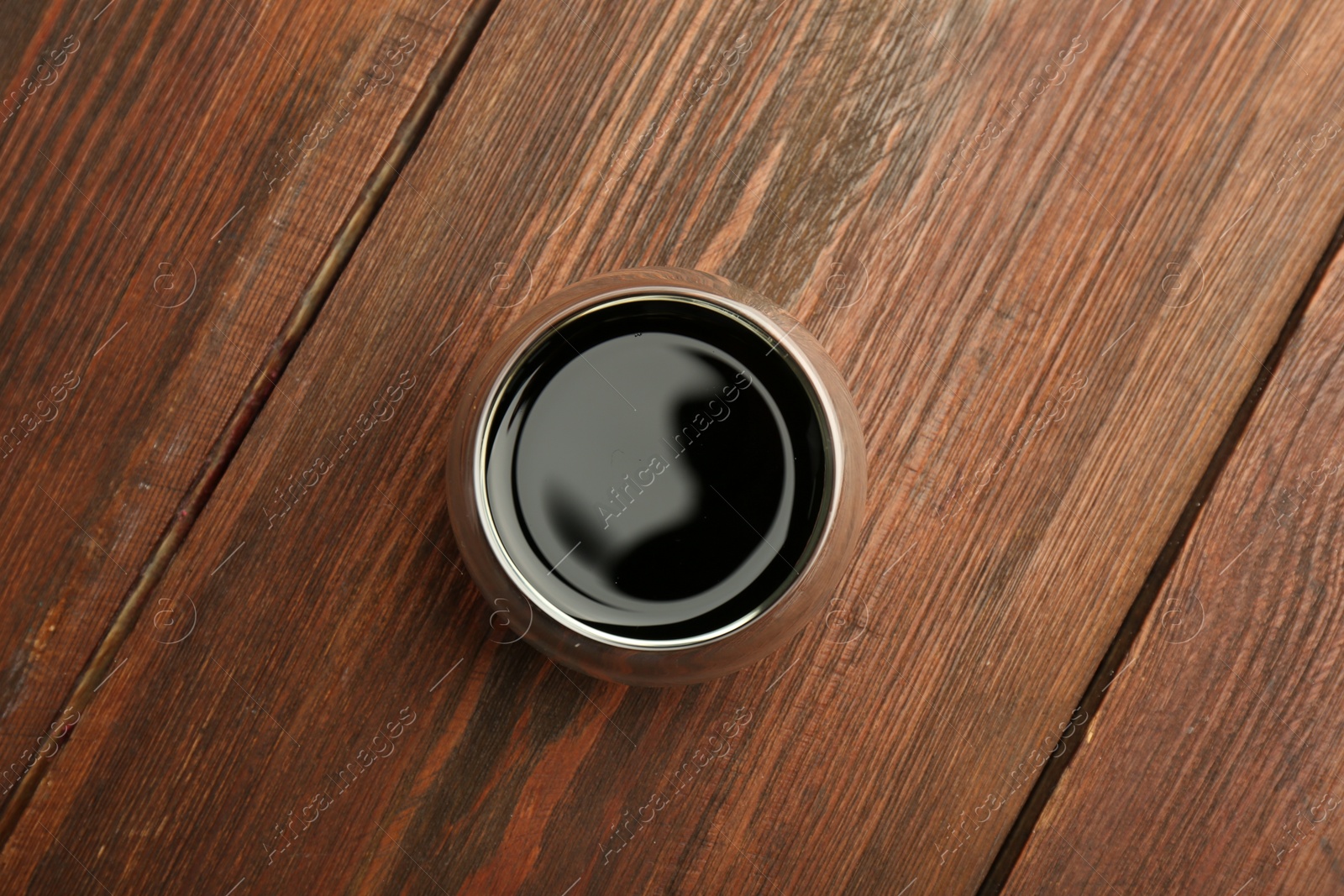 Photo of Soy sauce in bowl on wooden table, top view
