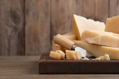 Photo of Delicious parmesan cheese with knife on wooden table. Space for text