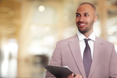 Image of Lawyer, consultant, business owner. Confident man with clipboard smiling indoors, space for text