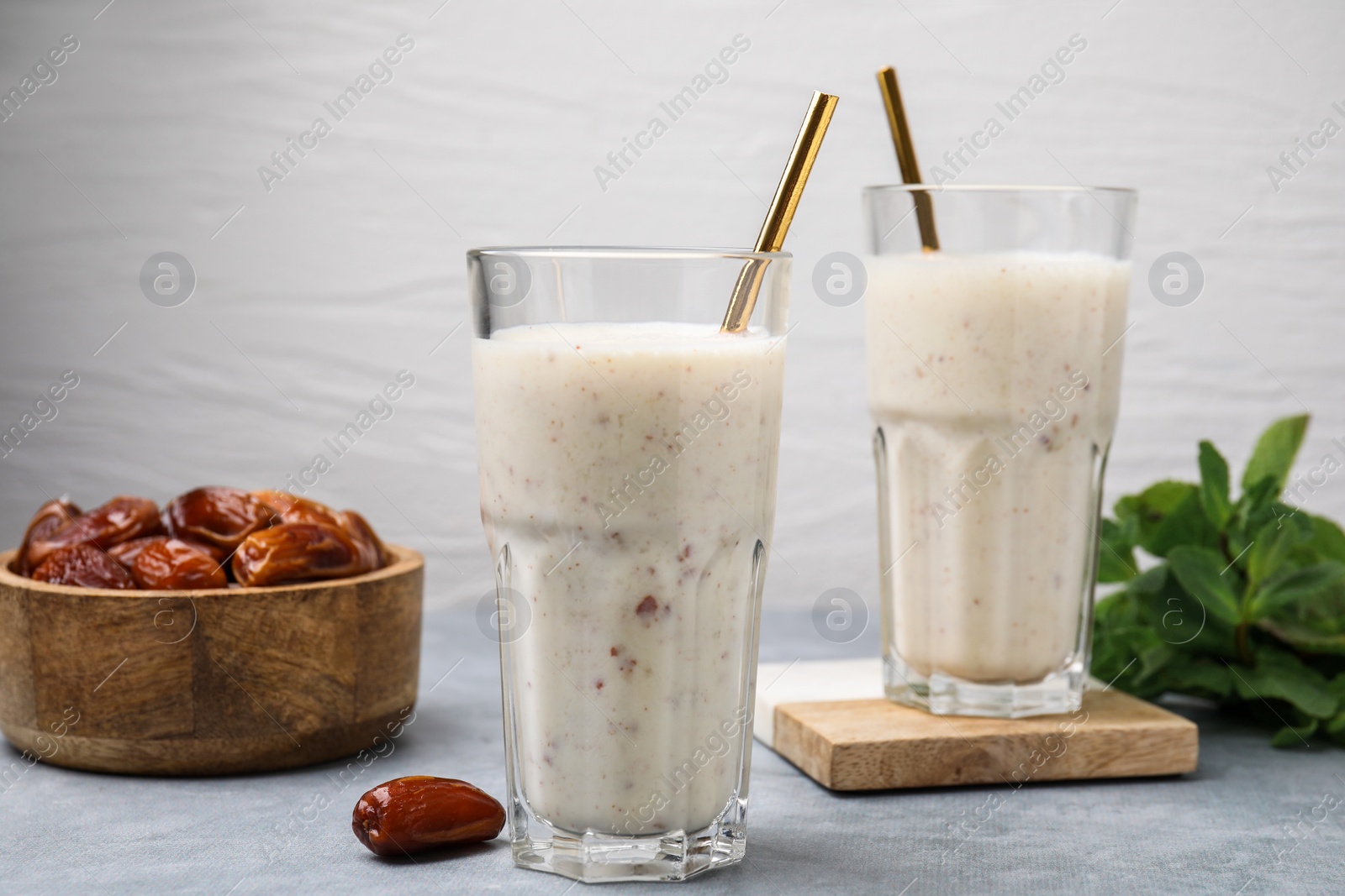 Photo of Glasses of delicious date smoothie and dried fruits on light grey table