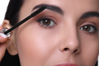 Beautiful young woman applying mascara, closeup view