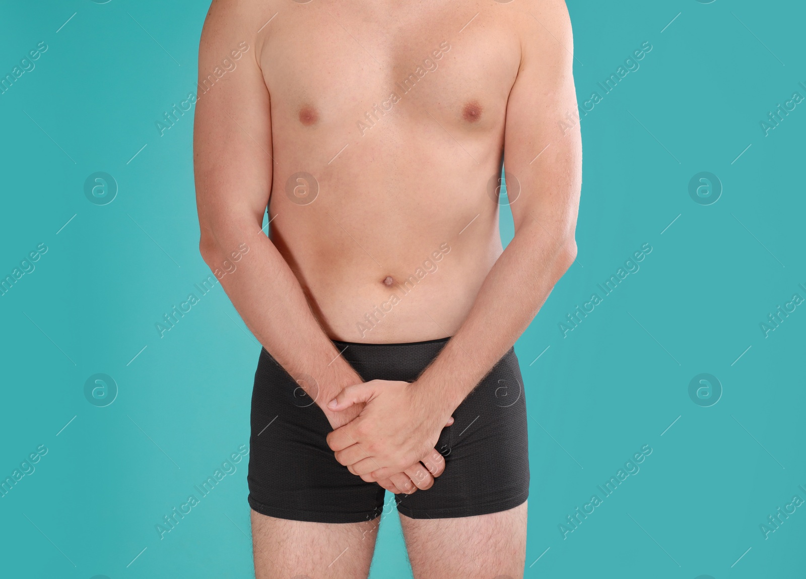 Photo of Man suffering from pain on turquoise background, closeup. Urology problems