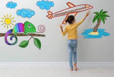Image of Cute child girl painting plane on light grey wall indoors