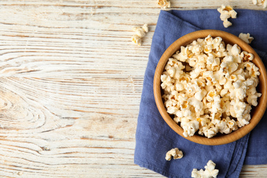 Photo of Tasty pop corn on white wooden table, flat lay. Space for text