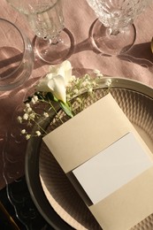 Stylish table setting. Plates, glasses, blank card and floral decor, top view